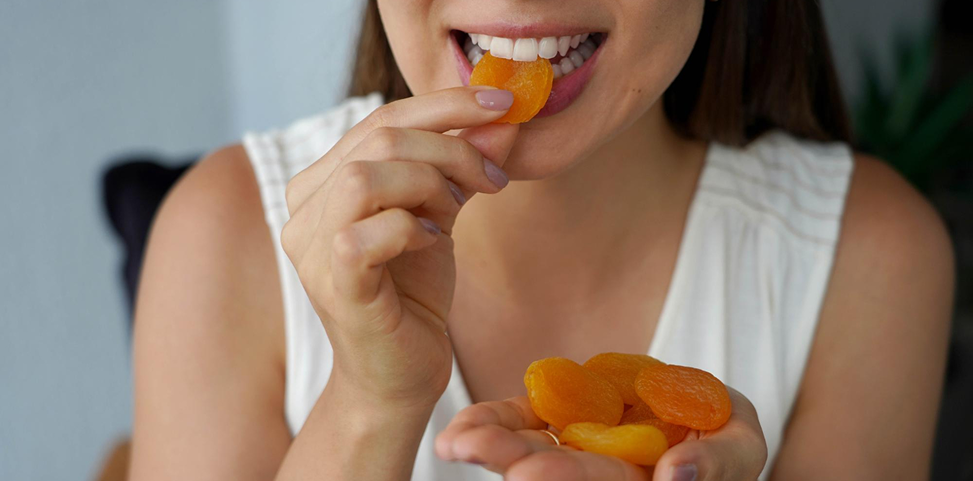 Woman eating dried fruit while showing her teeth in Tarneit